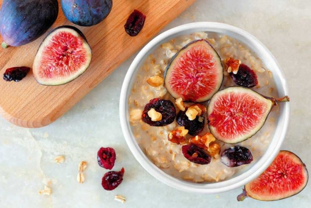Autumn oatmeal with red figs, cranberries and walnuts in a bowl, Autumn oatmeal with red figs, cranberries and walnuts in a bowl, overhead scene on white marble