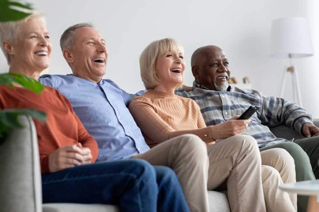 Multiracial friends senior people watching TV and laughing Multiracial friends senior people watching TV and laughing