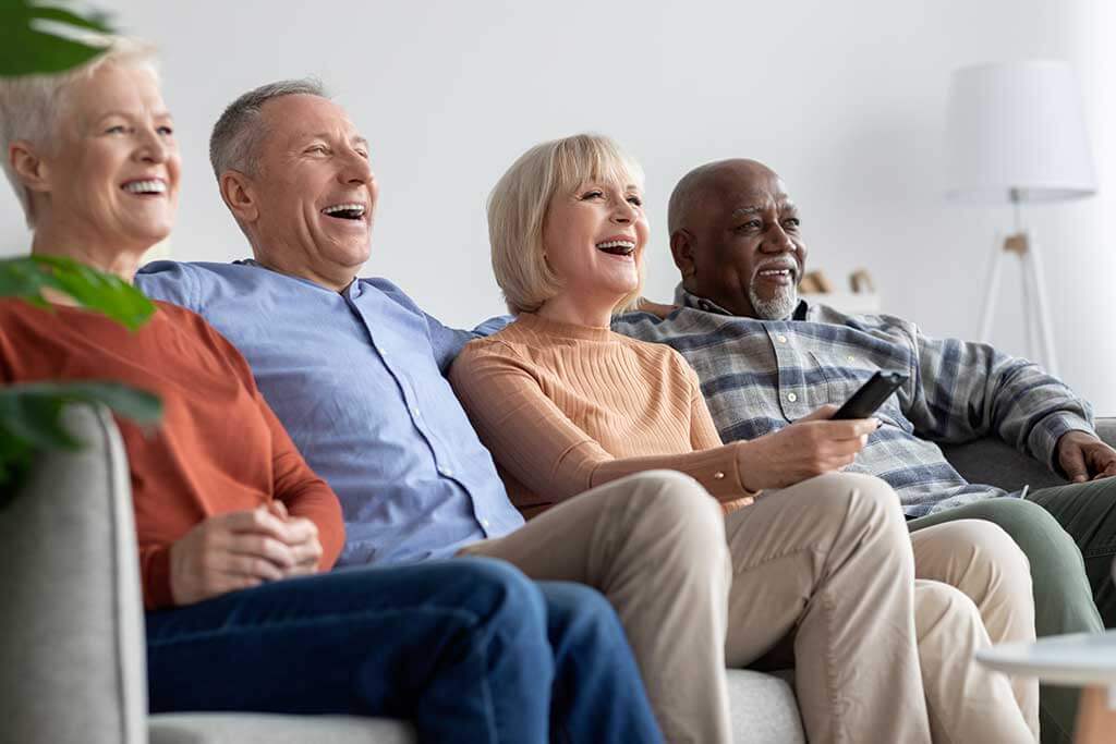 Multiracial friends senior people watching TV and laughing Multiracial friends senior people watching TV and laughing