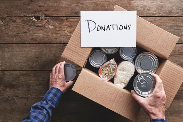 a person packing a donation box with food items a person packing a donation box with food items