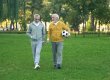 Active elderly men walking in park with football