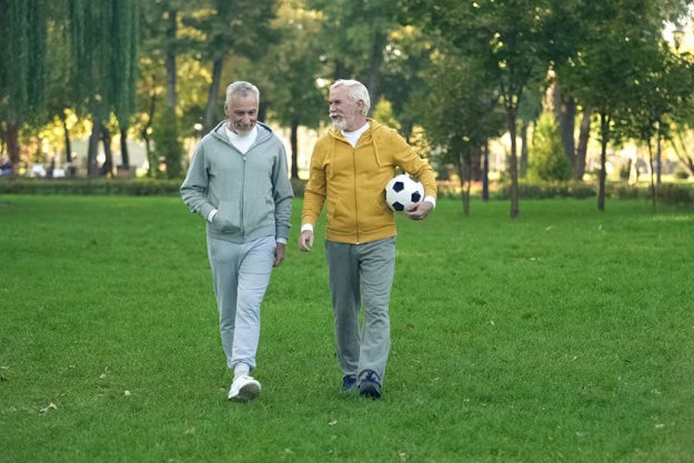 Active elderly men walking in park with football Active elderly men walking in park with football