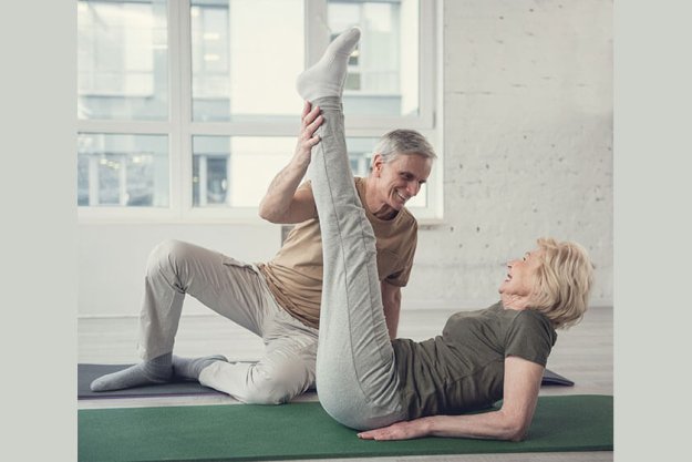 Cheerful aging woman lying on carpet with raised legs.