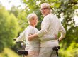 happy senior couple with bicycles at summer park
