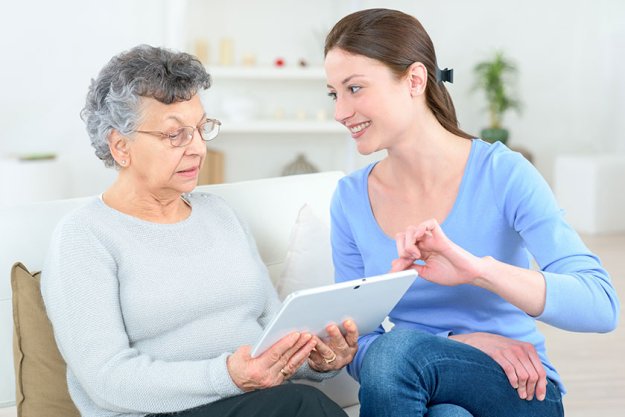 young lady helping elderly woman use a digital tablet young lady helping elderly woman use a digital tablet