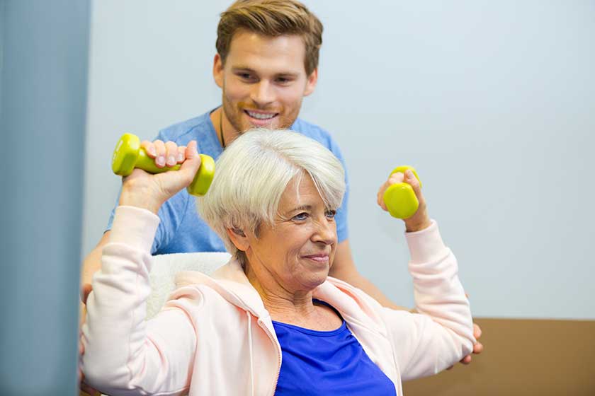 physiotherapist assisting senior woman to lift dumbbells physiotherapist assisting senior woman to lift dumbbells