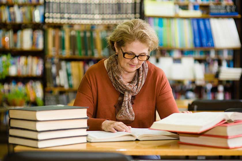 senior woman reading a book in the library