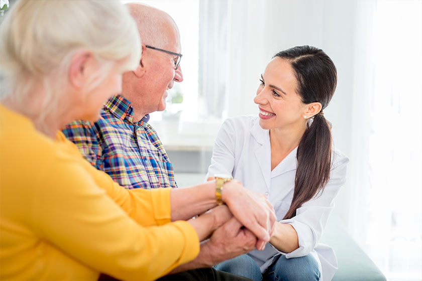 Smiling nurse talking with senior couple during home visit Smiling nurse talking with senior couple during home visit