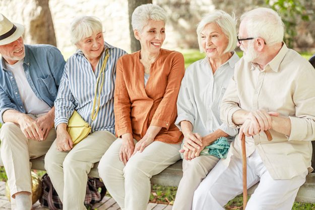 Cheerful senior people sitting on bench and chatting Cheerful senior people sitting on bench and chatting