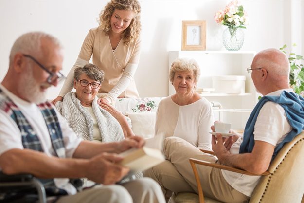 Group of senior friends sitting together at nursing home living room Group of senior friends sitting together at nursing home living room