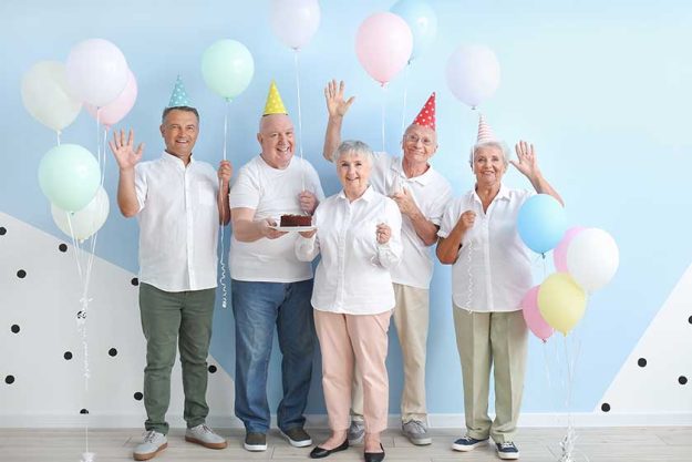 Senior people celebrating Birthday near color wall Senior people celebrating Birthday near color wall