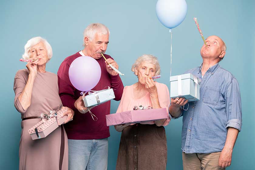 Two senior couples with giftboxes blowing whistles Two senior couples with giftboxes blowing whistles