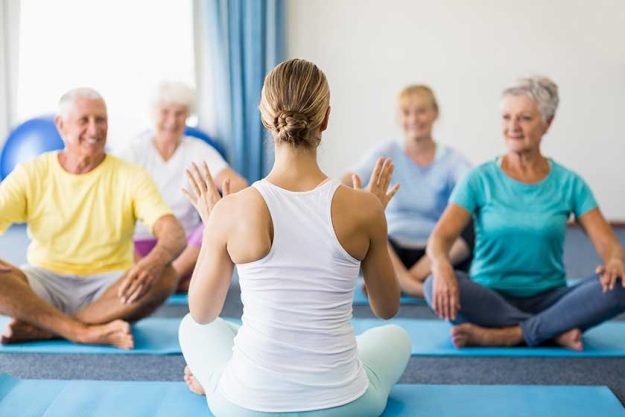 Instructor performing yoga with seniors Instructor performing yoga with seniors