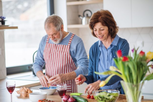 A portrait of senior couple in love indoors at home, cooking. How A Senior Community In Bixby, OK Makes Cooking Much Safer