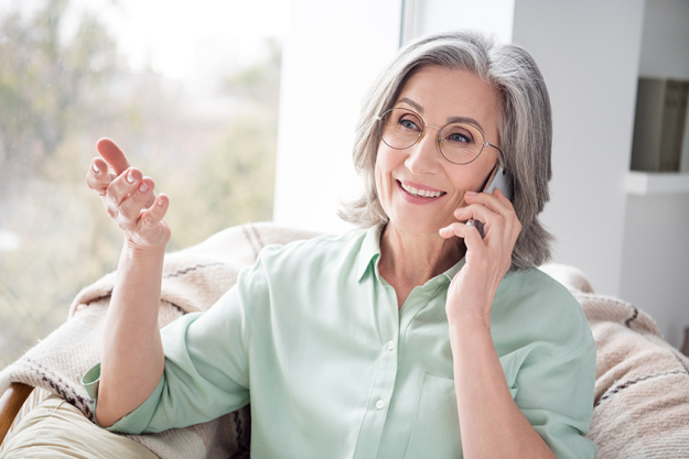 portrait-of-satisfied-charming-woman-sit-on-chair-near-window-speak-phone portrait-of-satisfied-charming-woman-sit-on-chair-near-window-speak-phone