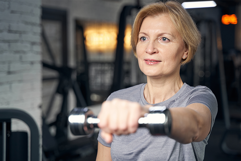Woman doing exercise with dumbbell in fitness