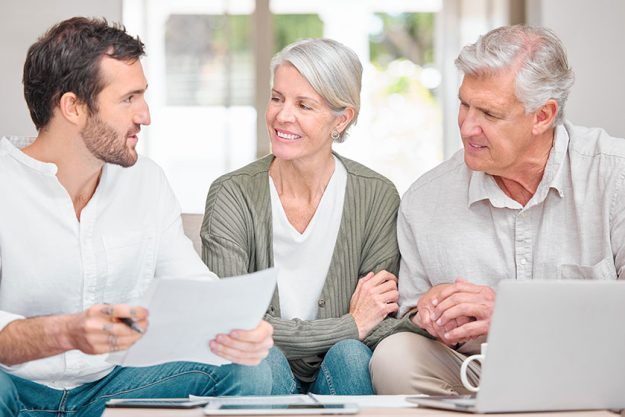 A handsome young male financial advisor helping a senior couple