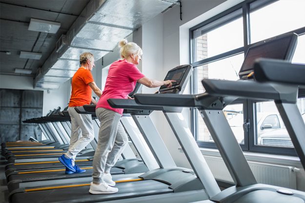 Senior people walking on treadmill at gym