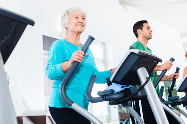 Senior woman on elliptical trainer exercising in gym Senior woman on elliptical trainer exercising in gym