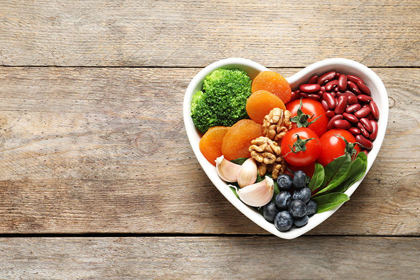 Bowl with heart-healthy diet products on wooden background, top view. Space for text