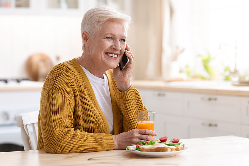 Cheerful grandmother having phone call while eating at home Cheerful grandmother having phone call while eating at home
