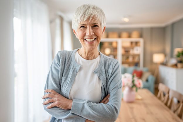 Close up portrait of one senior woman with short hair happy smile positive emotion copy space standing at home indoor gray white hair