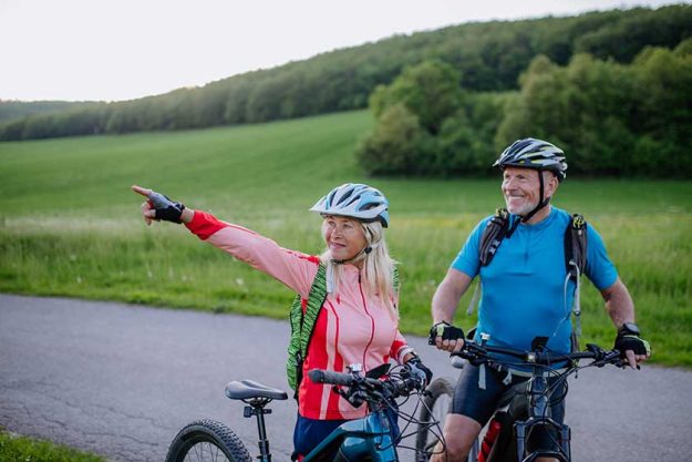 An ctive senior couple riding electric bicycles on road