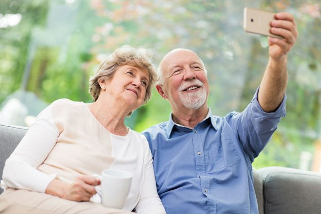 Cute senior couple taking selfie at home for social media Cute senior couple taking selfie at home for social media