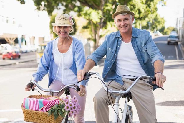 Happy mature couple going for a bike ride in the city