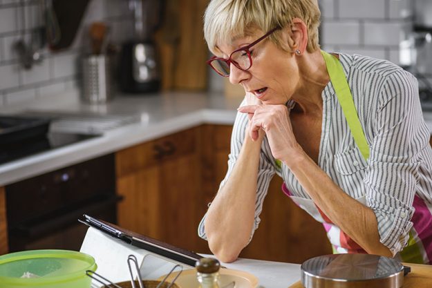 Beautiful senior woman reading recipe on tablet