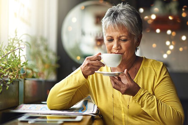 Senior woman, tea and smile in cafe for relax, style and free time for fashion, retired and elderly in outdoor. African person and pensioner with cup for unwind, hairstyle and happy on mockup.