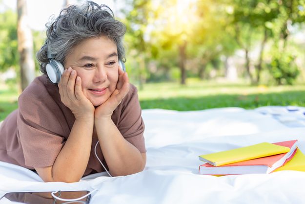 Senior-happy-woman-listening-music-at-park-by-wear-headphone