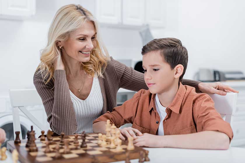 Middle-aged-woman-smiling-grandson-playing-chess-kitchen Middle-aged-woman-smiling-grandson-playing-chess-kitchen