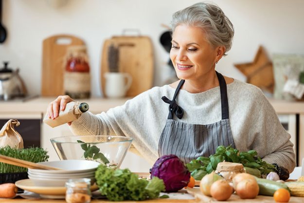Cheerful middle aged housewife in apron pours