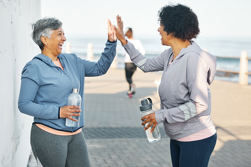 Fitness, happy and women high five by ocean Fitness, happy and women high five by ocean