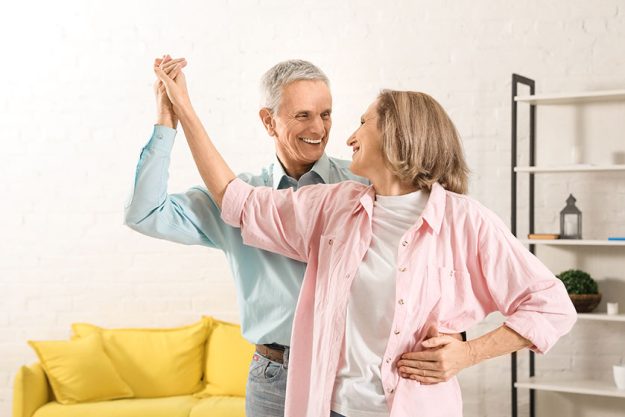 Happy senior couple dancing together in living room