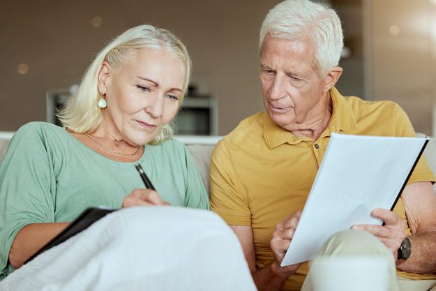 Mature couple, home and savings with paperwork