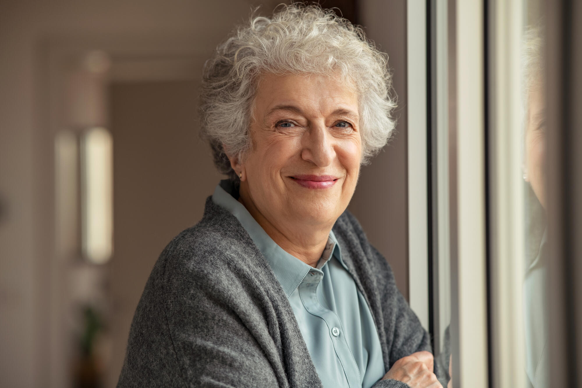 Portrait,Of,Happy,Senior,Woman,Standing,At,Home,Near,Window