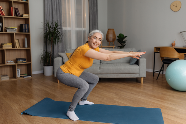 active-senior-lady-doing-squats-domestic-workout Active senior lady doing squats