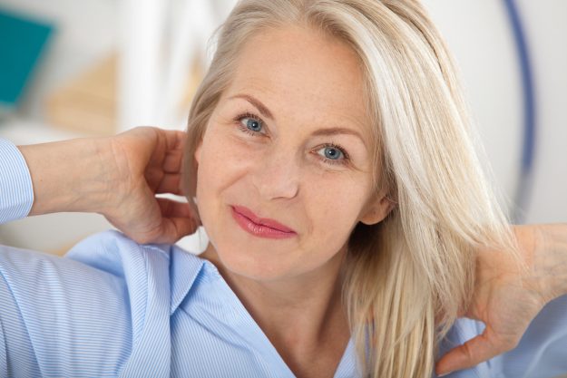 Modern businesswoman. Beautiful middle aged woman looking at camera with smile while siting in the office.