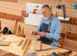 Mature carpenter working with wooden plank