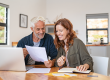 Mature smiling couple sitting and managing expenses