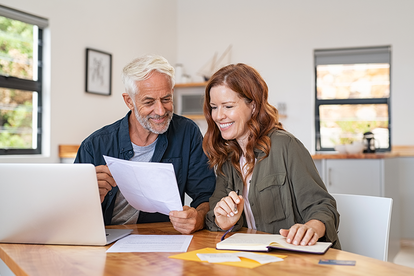 mature-smiling-couple-sitting-managing-expenses Mature smiling couple sitting and managing expenses