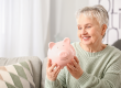 Senior woman with piggy bank at home