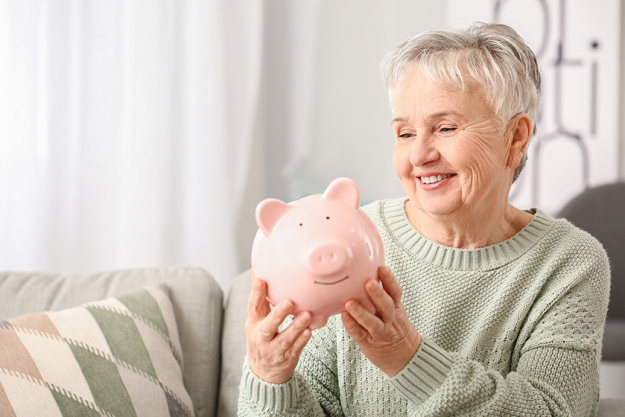 senior-woman-piggy-bank Senior woman with piggy bank at home